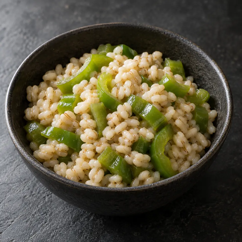 Adlai Bellpepper Rice in a bowl on a dark stone table, made with capsicum - green, adlai rice, a grain that looks like pearl barley).