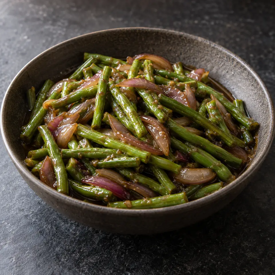 Adobong Sitaw on a plate on a dark stone table, made with sitaw, red onion.