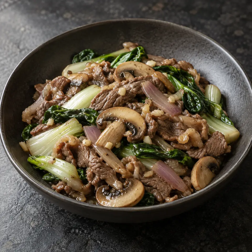 Beef with Mushroom on a plate on a dark stone table, made with ginisang pechay, beef sukiyaki meat, button, lemon juice.