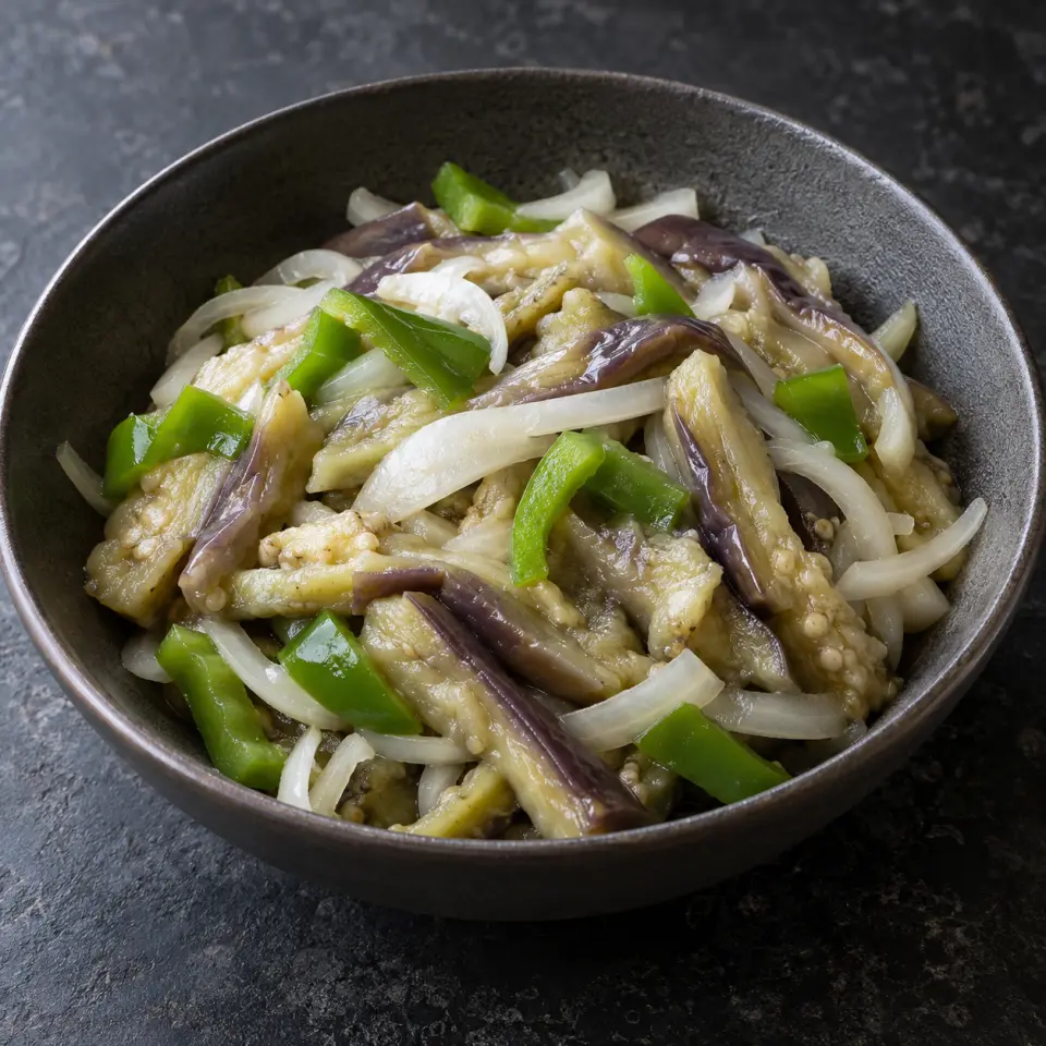 Boiled Eggplant Ensalada in a wide bowl on a dark stone table, made with eggplant, white onion, capsicum green.