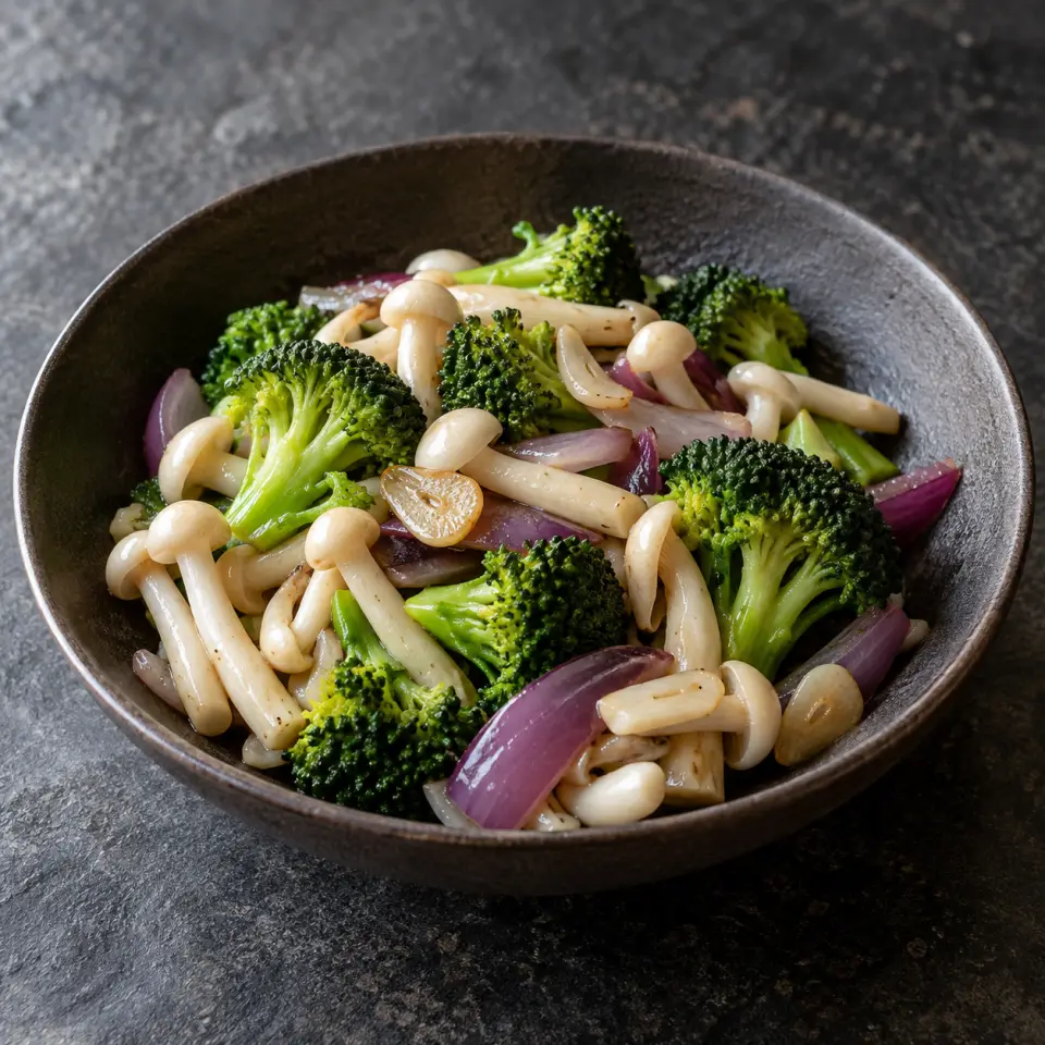 Broccoli White Beech Mushrooms on a plate on a dark stone table, made with white beech mushrooms, broccoli, red onion, garlic.