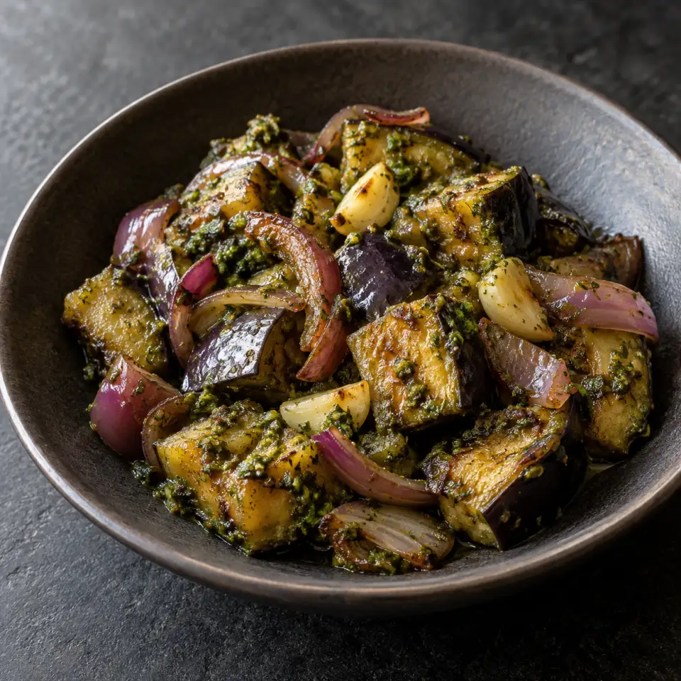 Eggplant Bellpepper Pesto on a plate on a dark stone table, made with pesto, eggplant, red onion, garlic.
