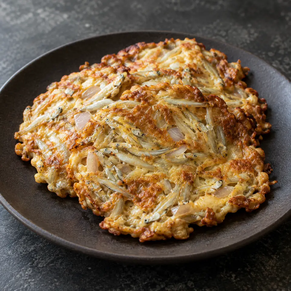 Tortang Dulong on a plate on a dark stone table, made with silverfish, egg, onion, garlic.